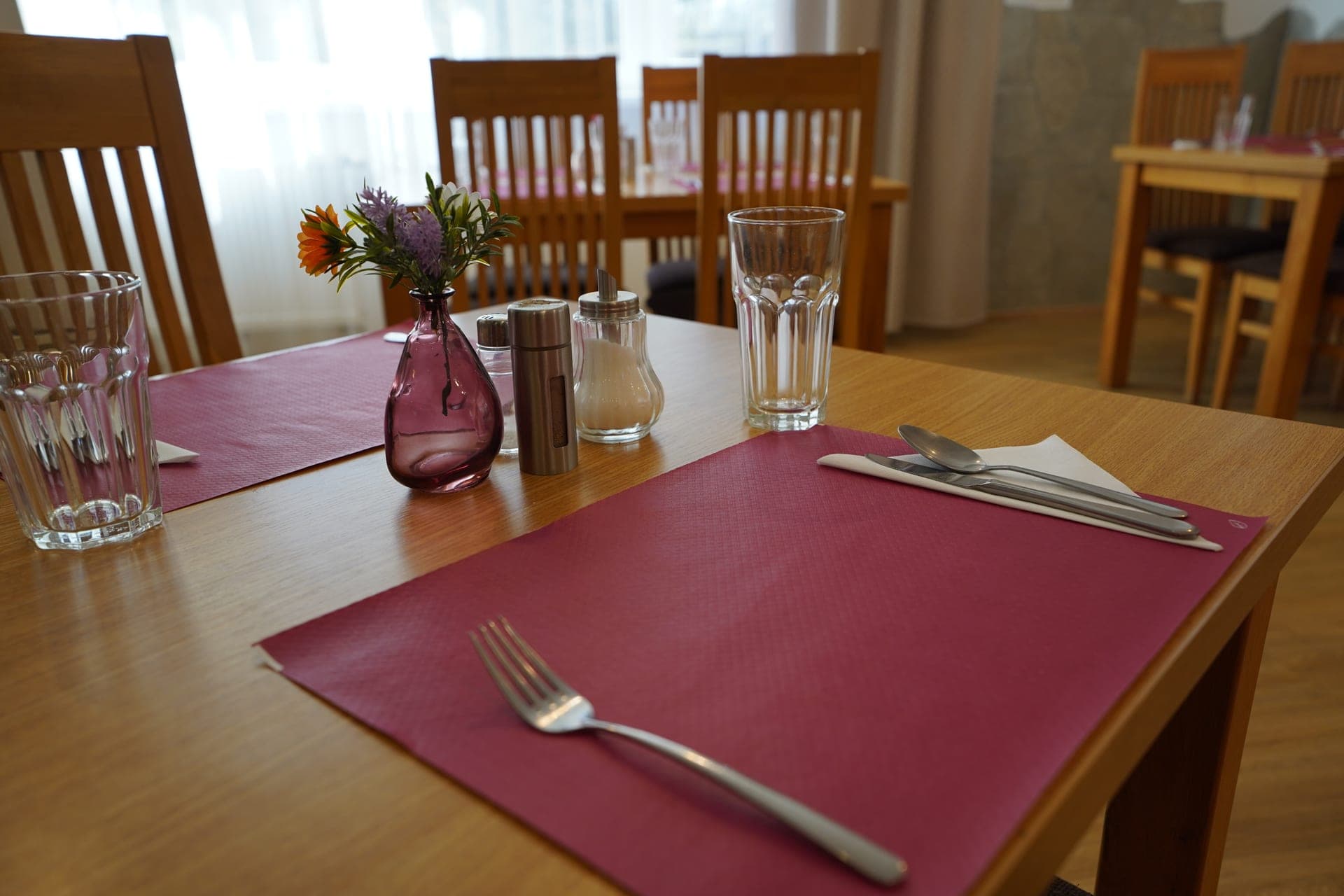 Prostřený stůl v restauraci Observatoř — dřevěné stoly, vínové prostírání, čerstvé květiny